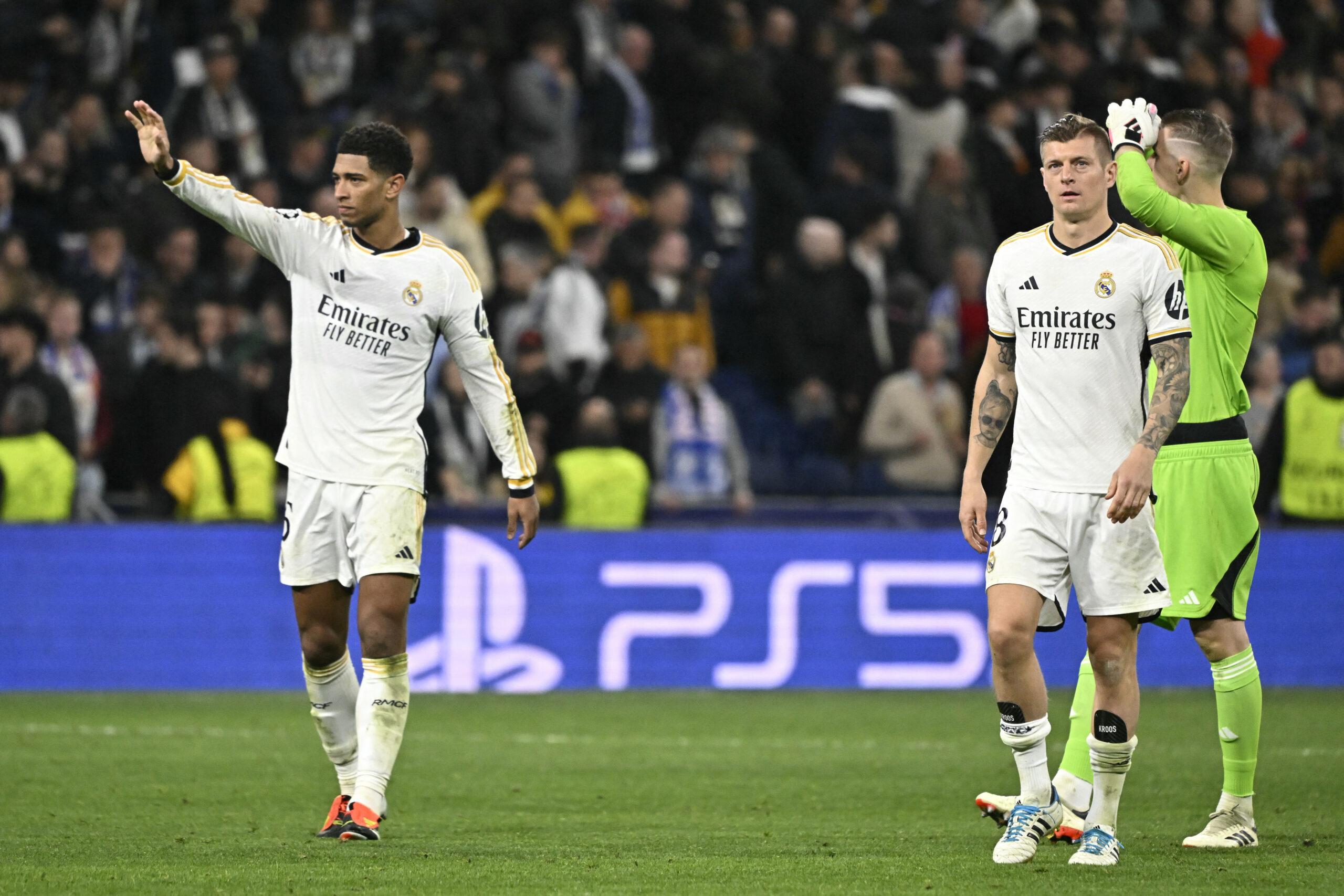 (From L) Real Madrid's English midfielder #5 Jude Bellingham, Real Madrid's German midfielder #08 Toni Kroos and Real Madrid's Ukrainian goalkeeper #13 Andriy Lunin walk on the pitch at the end of the UEFA Champions League last 16 second leg football match between Real Madrid CF and RB Leipzig at the Santiago Bernabeu stadium in Madrid on March 6, 2024.