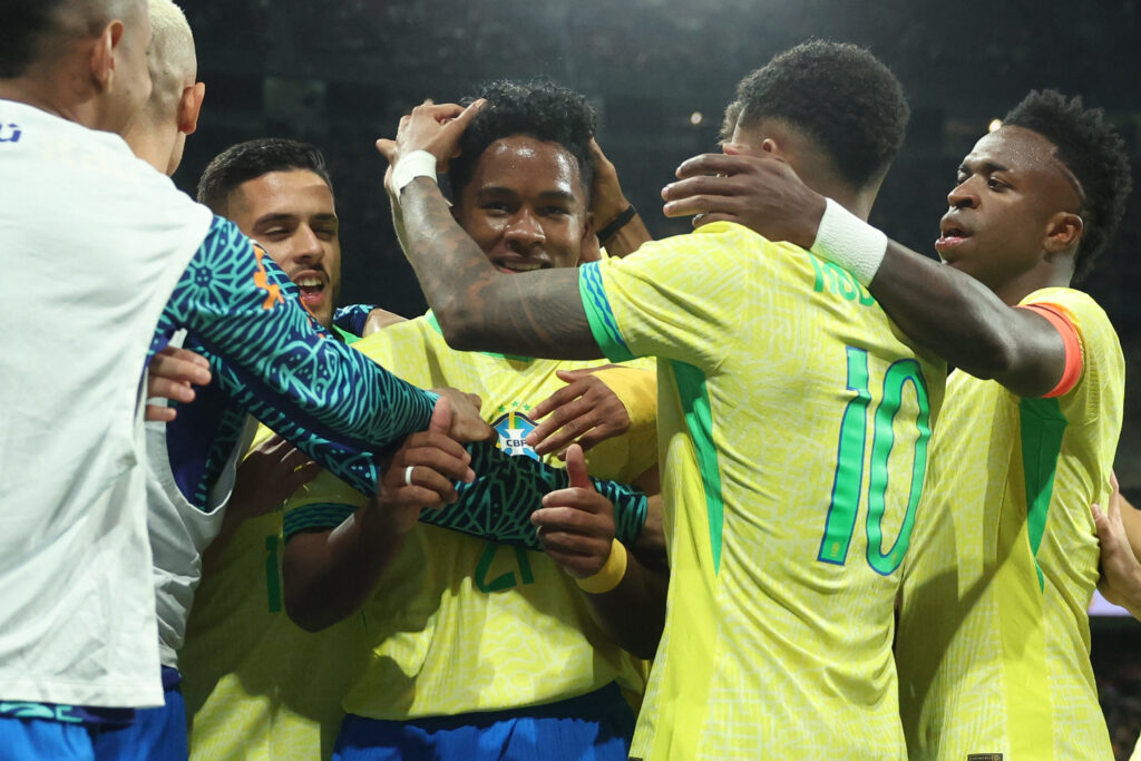 TOPSHOT - Brazil's forward #21 Endrick celebrates with teammates scoring his team's second goal during the international friendly football match between Spain and Brazil at the Santiago Bernabeu stadium in Madrid, on March 26, 2024. Spain arranged a friendly against Brazil at the Santiago Bernabeu under the slogan "One Skin" to help combat racism.