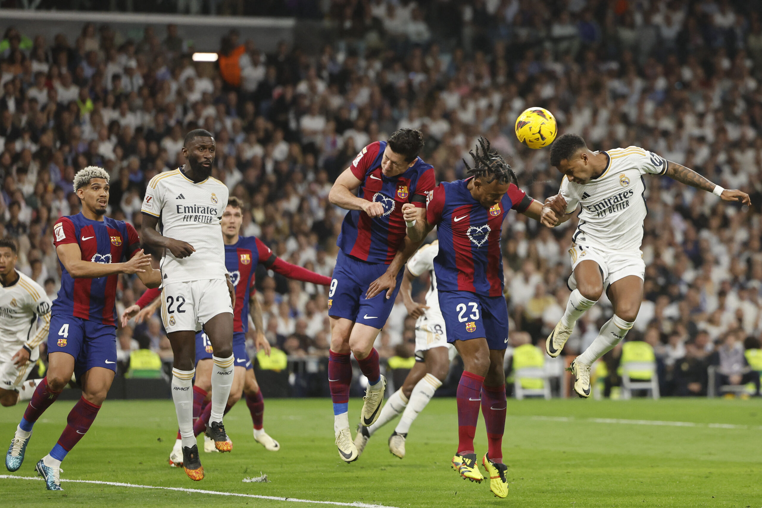 Real Madrid's Brazilian forward #11 Rodrygo (R), Barcelona's French defender #23 Jules Kounde and Barcelona's Polish forward #09 Robert Lewandowski vie for a a header during the Spanish league football match between Real Madrid CF and FC Barcelona at the Santiago Bernabeu stadium in Madrid on April 21, 2024.