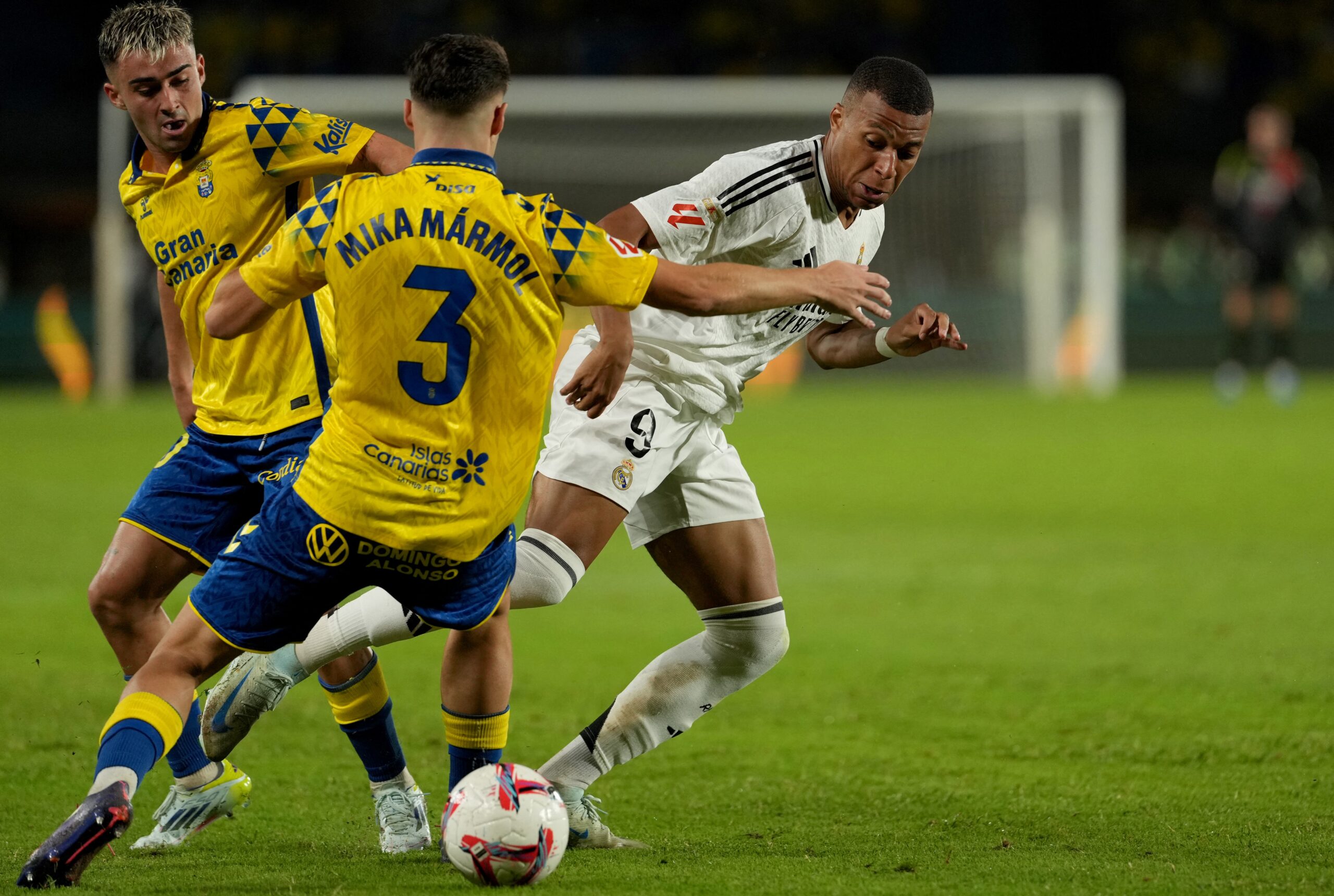 Real Madrid's French forward #09 Kylian Mbappe fights for the ball with Las Palmas' Spanish defender #03 Mika Marmol and Las Palmas' Spanish midfielder #10 Alberto Moleiro during the Spanish league football match between UD Las Palmas and Real Madrid CF at the Gran Canaria stadium in Las Palmas de Gran Canaria on August 29, 2024.