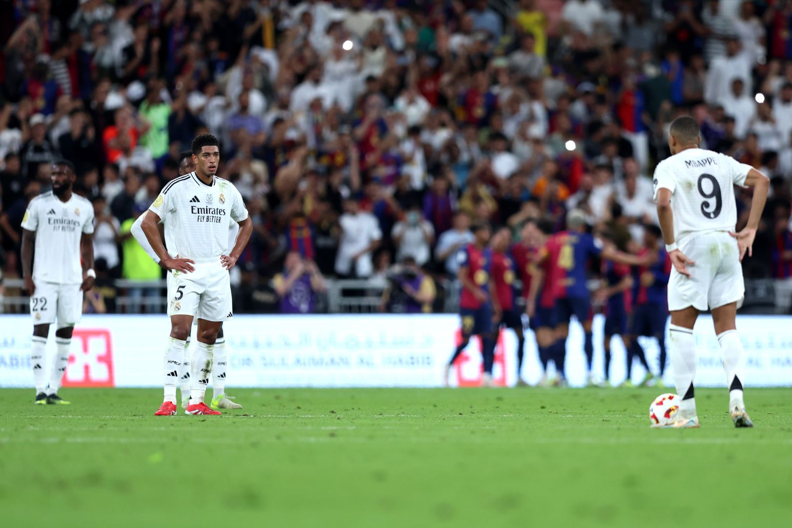 JEDDAH, SAUDI ARABIA - JANUARY 12: Jude Bellingham of Real Madrid looks to team mate Kylian Mbappe as Raphinha of FC Barcelona (obscured) celebrates scoring his team's third goal during the Spanish Super Cup Final between Real Madrid and FC Barcelona at King Abdullah Sports City on January 12, 2025 in Jeddah, Saudi Arabia.