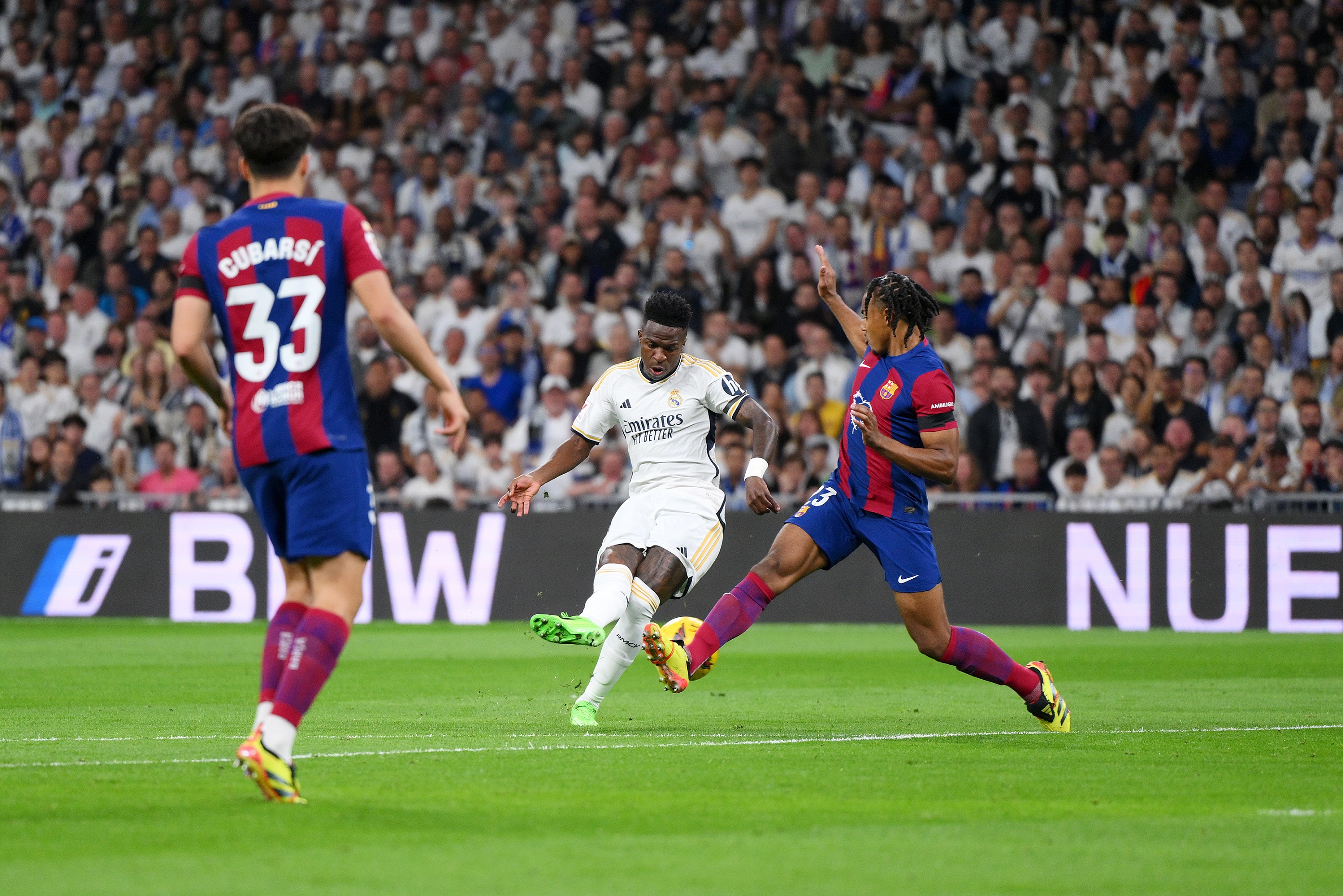 MADRID, SPAIN - APRIL 21: Vinicius Junior of Real Madrid takes a shot whilst under pressure from Jules Kounde of FC Barcelona during the LaLiga EA Sports match between Real Madrid CF and FC Barcelona at Estadio Santiago Bernabeu on April 21, 2024 in Madrid, Spain.