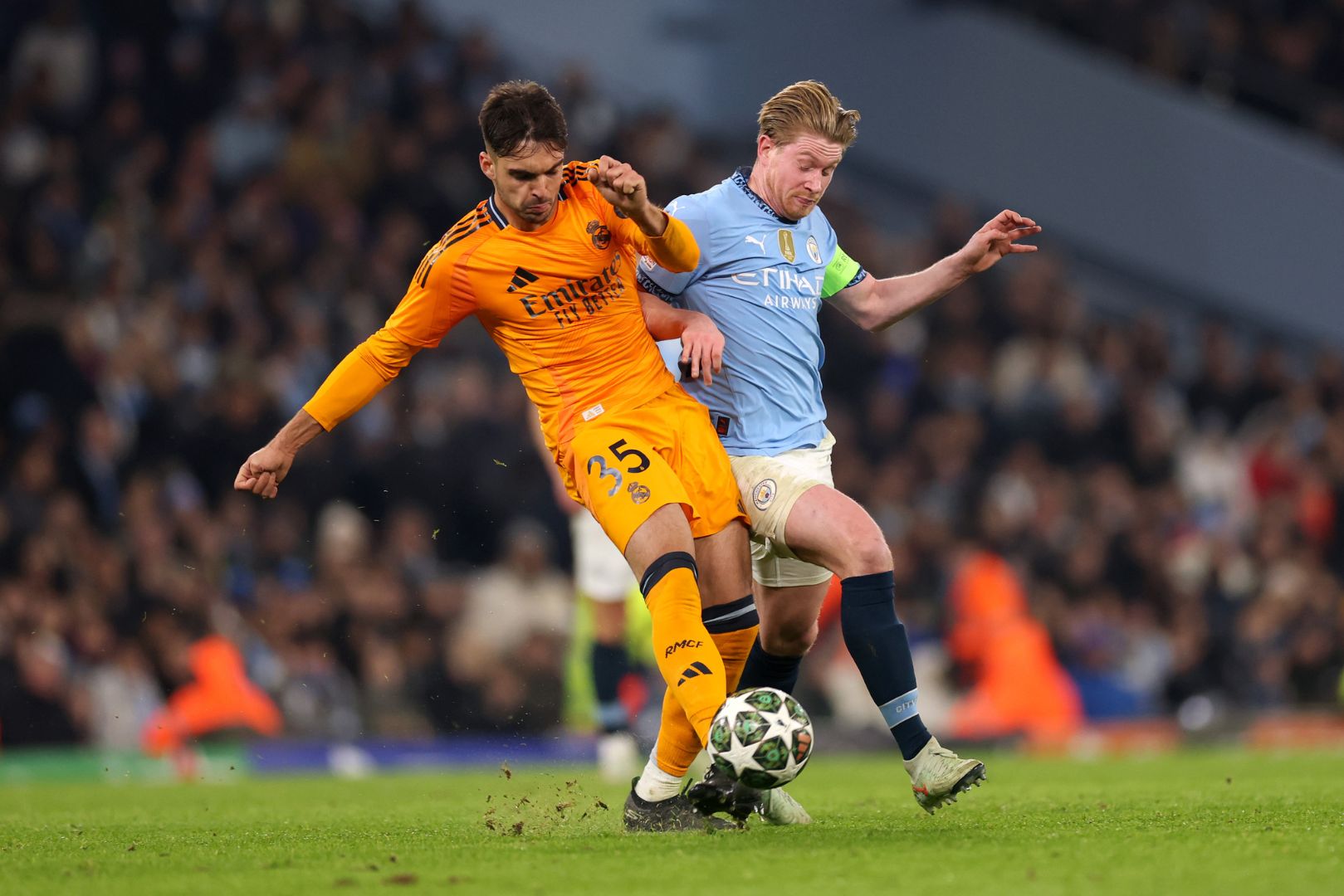 MANCHESTER, ENGLAND - FEBRUARY 11: Raul Asencio of Real Madrid is challenged by Kevin De Bruyne of Manchester City during the UEFA Champions League 2024/25 League Knockout Play-off first leg match between Manchester City and Real Madrid C.F. at Manchester City Stadium on February 11, 2025 in Manchester, England.