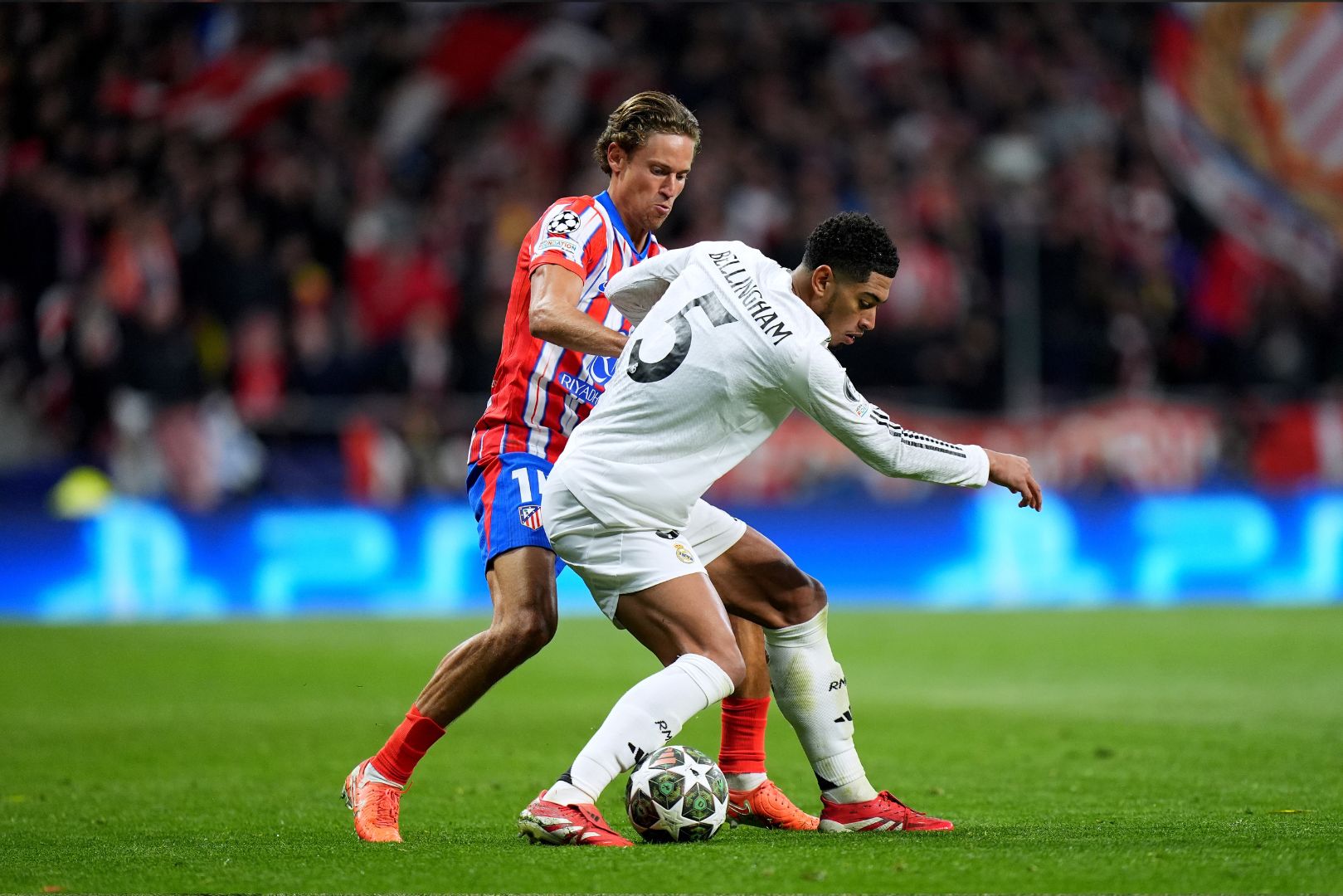MADRID, SPAIN - MARCH 12: Jude Bellingham of Real Madrid is challenged by Marcos Llorente of Atletico de Madrid during the UEFA Champions League 2024/25 Round of 16 second leg match between Atletico de Madrid and Real Madrid C.F. at Estadio Metropolitano on March 12, 2025 in Madrid, Spain.